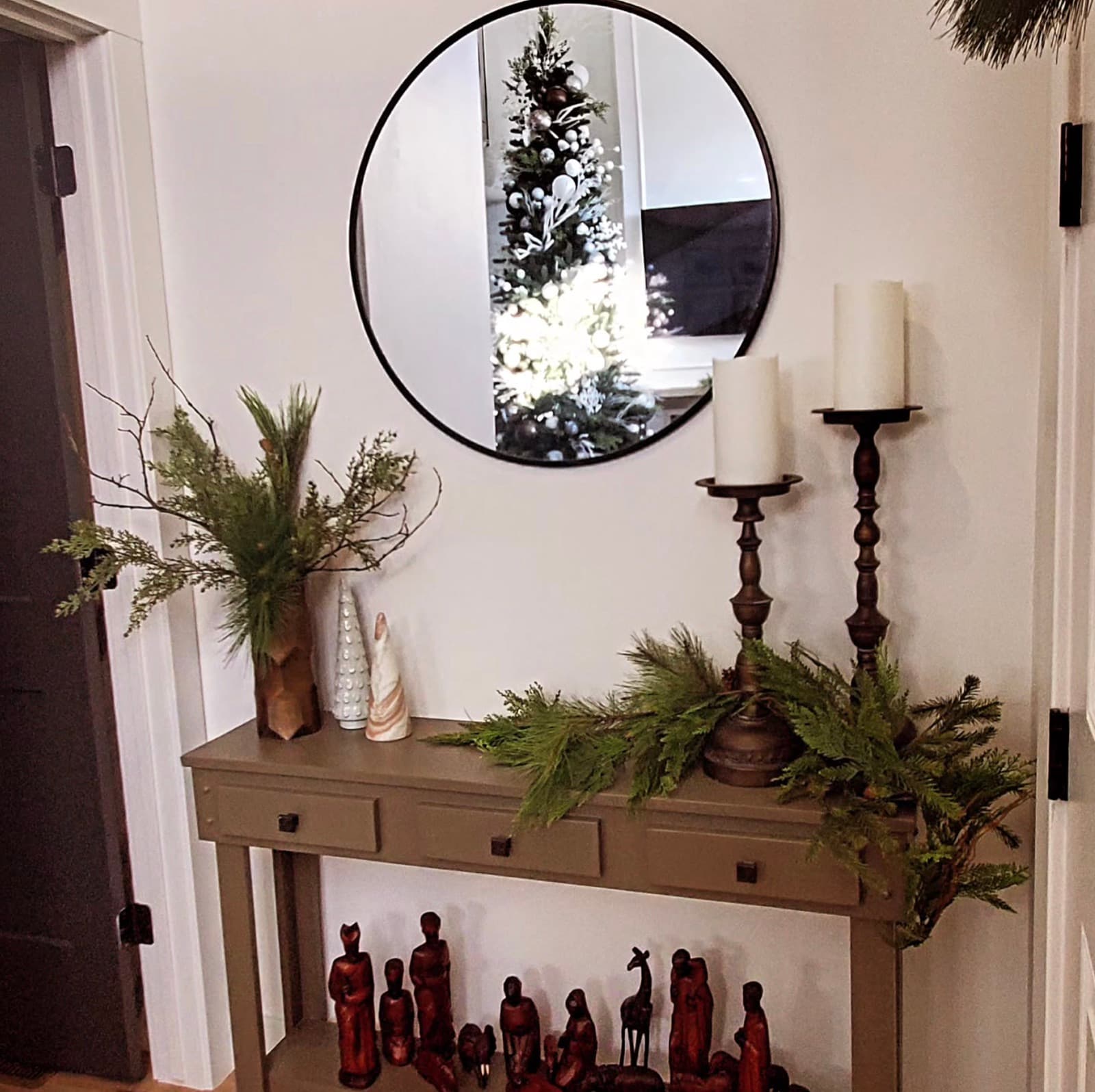 Entryway console styled with fresh greenery, pillar candles and a nativity set