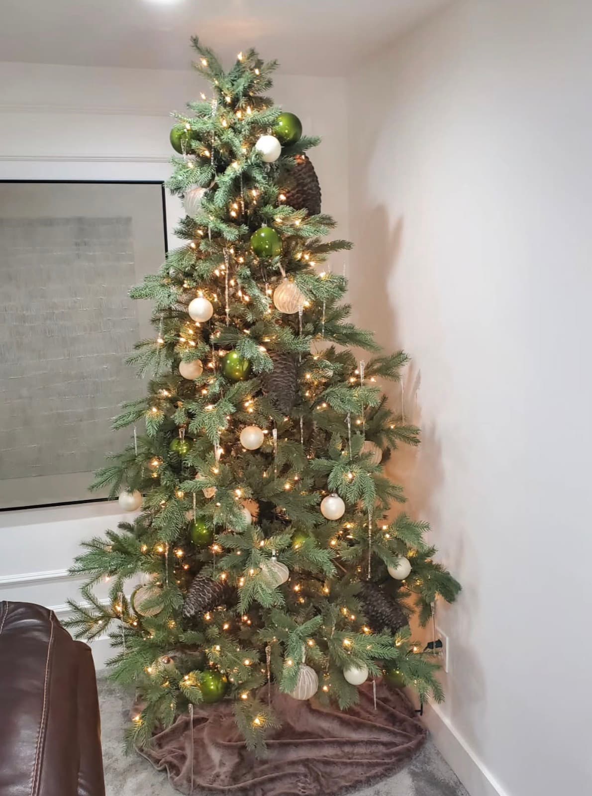 Christmas tree with green and cream ornaments, oversized pinecones and icicles